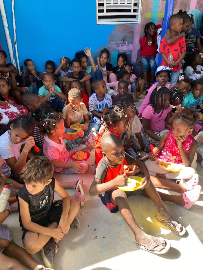 Children eating, seated on the floor of the kitchen