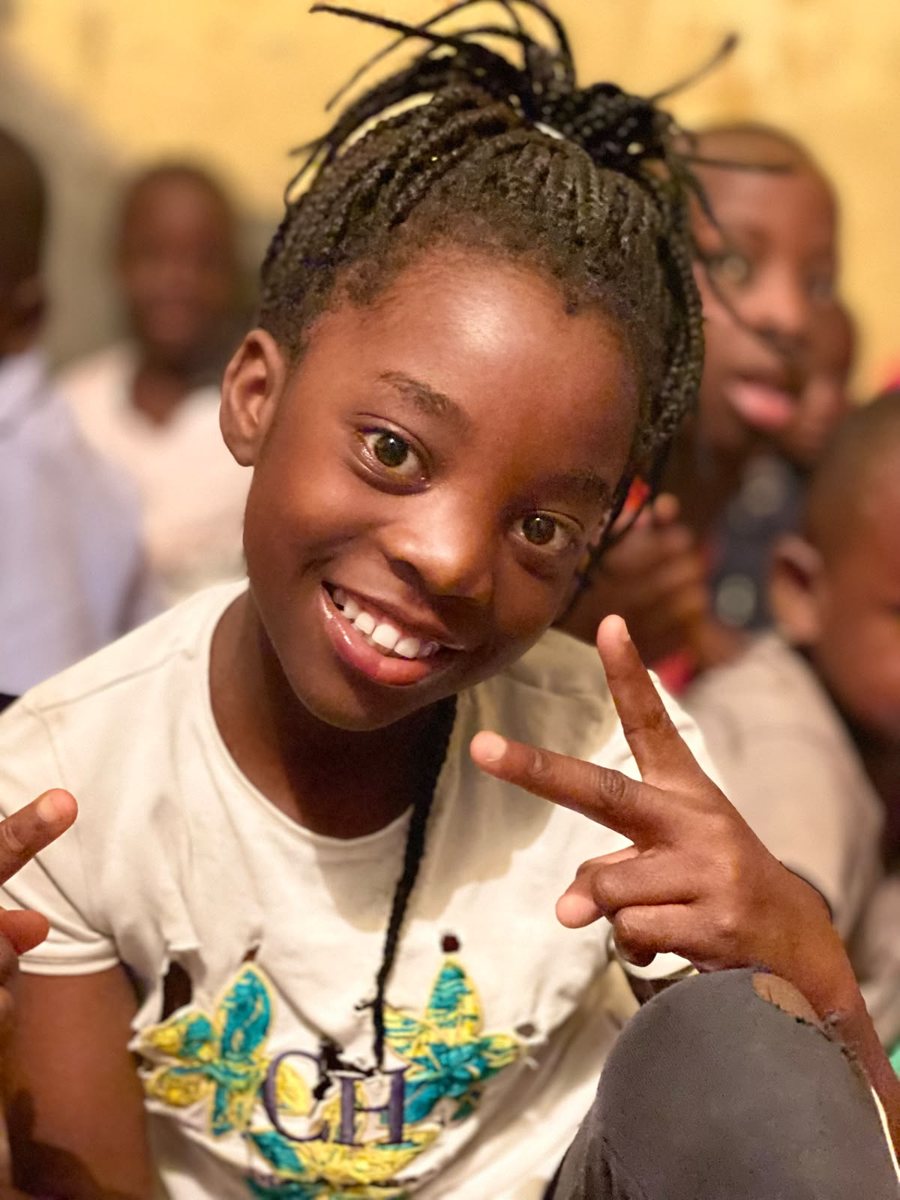 A girl at the community kitchen smiles and makes a peace sign