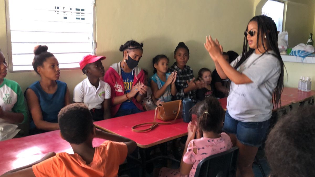 A volunteer sings and claps with the children in the classroom