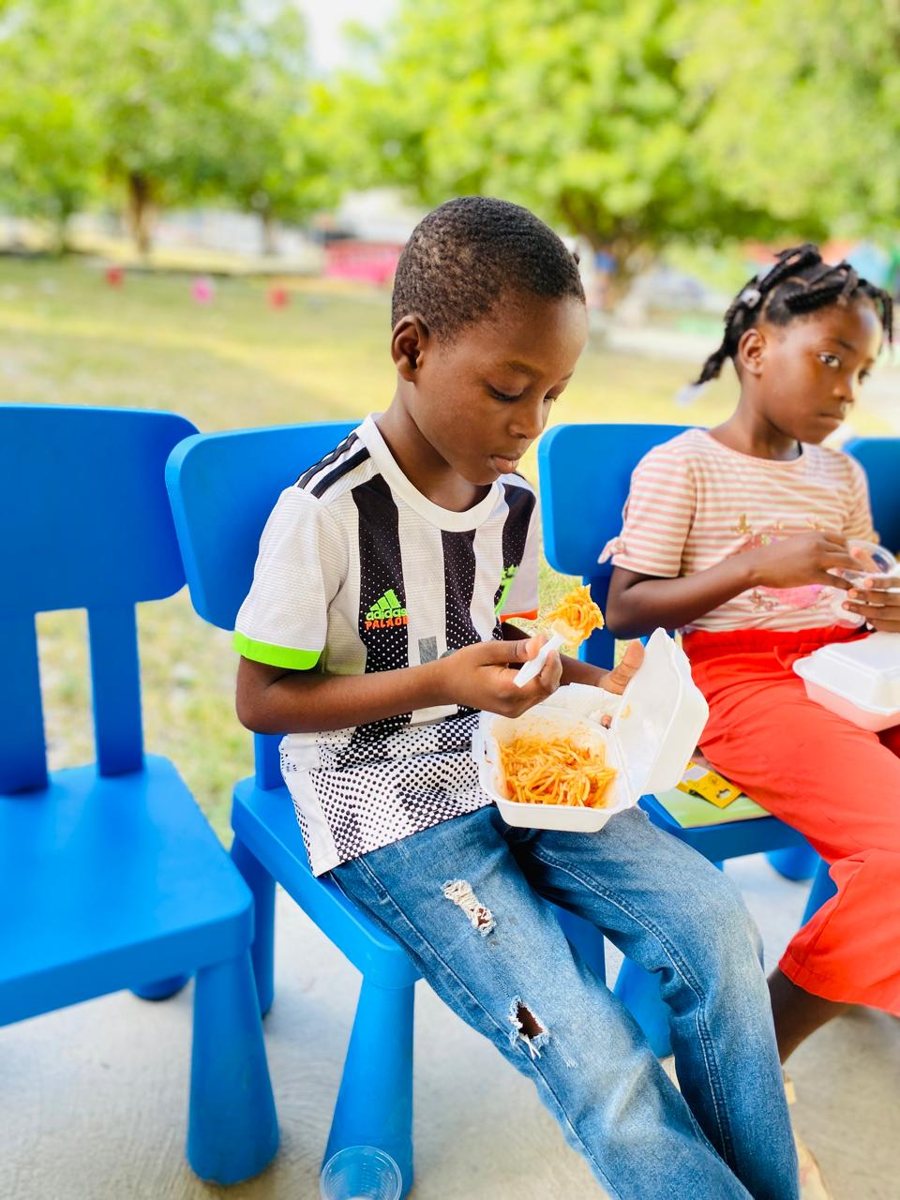 A boy and a girl eat lunch on blue chairs outdoors